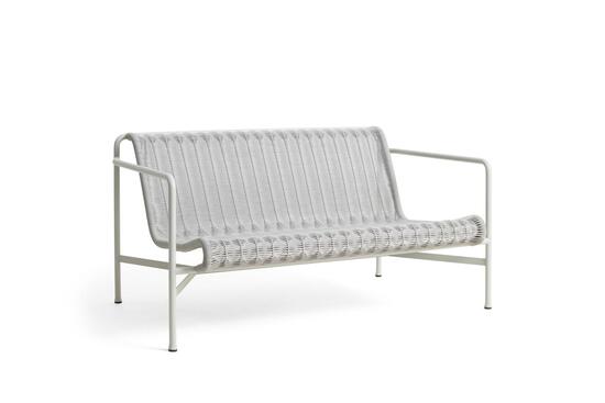 Sofa i minimalistisk design med buede armlæn og slatted ryg. Farve: lysegrå.