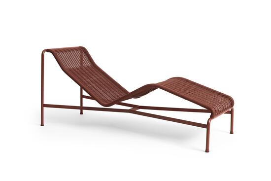 Chaiselongue i jernrød med buet ramme og flettet tekstur. Minimalistisk design med fire ben.